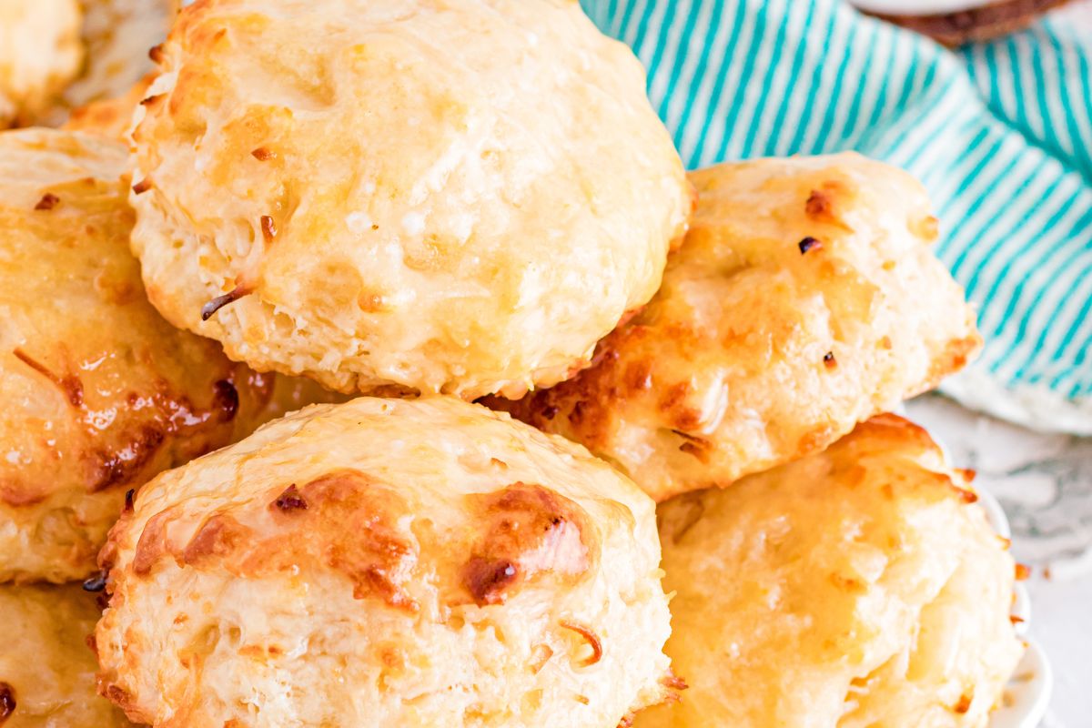 Close-up of a stack of golden-brown cheese biscuits on a plate, with a green striped cloth partially visible in the background—perfect for anyone who loves exploring biscuit recipes.