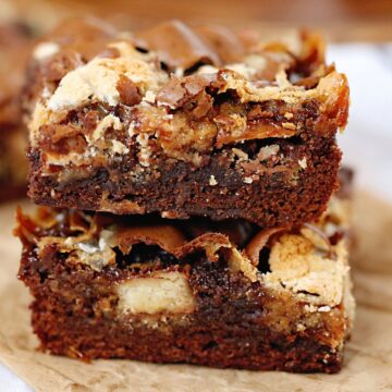 Two brownies stacked on a piece of brown parchment paper.