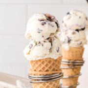Two cones filled with scoops of lemon blueberry ice cream being held by metal stands.