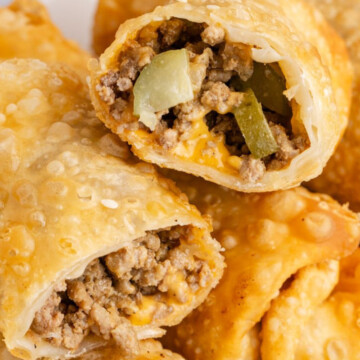 A pile of egg rolls with top one cut in half.