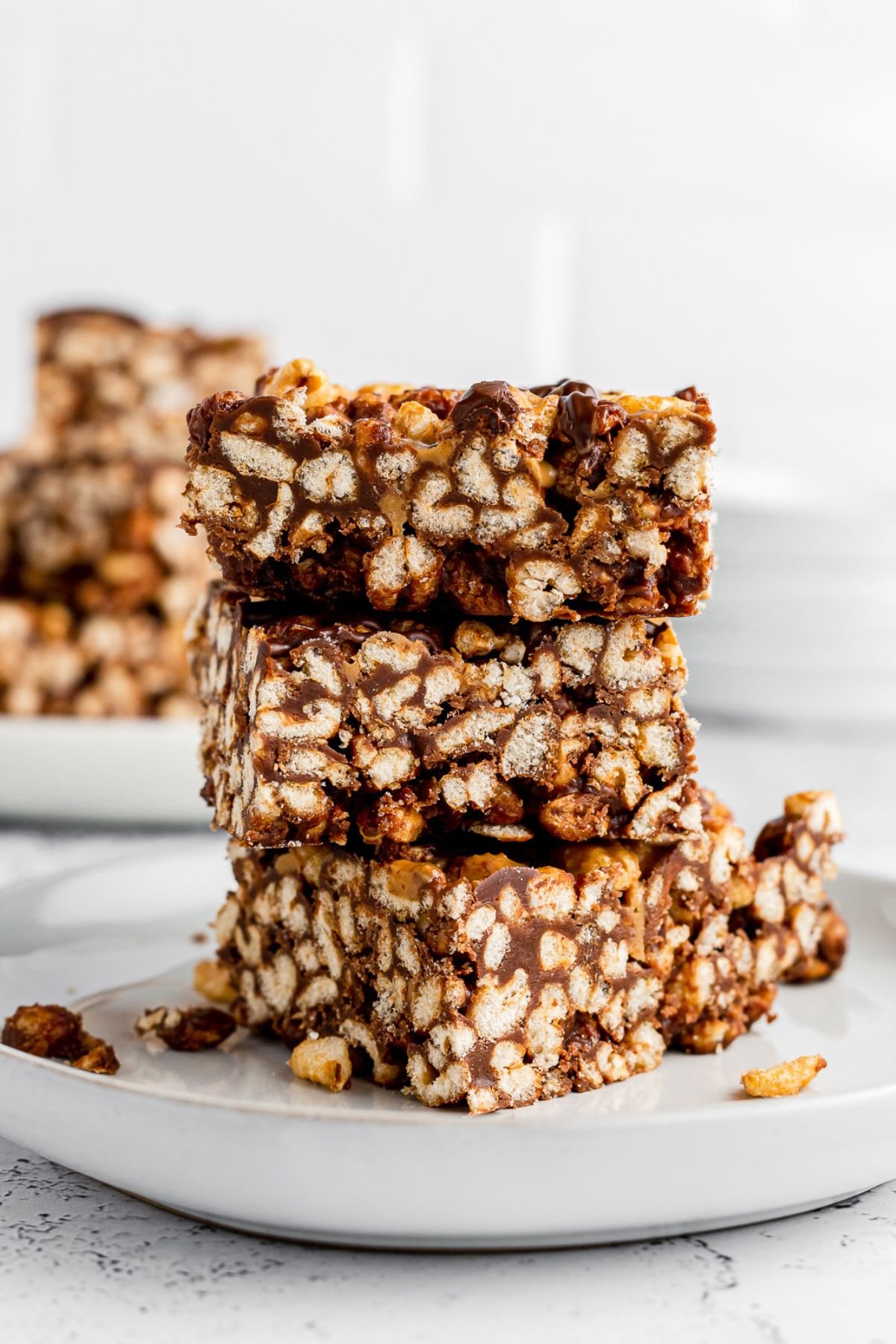 Three marshmallow cereal bars stacked on a white plate.