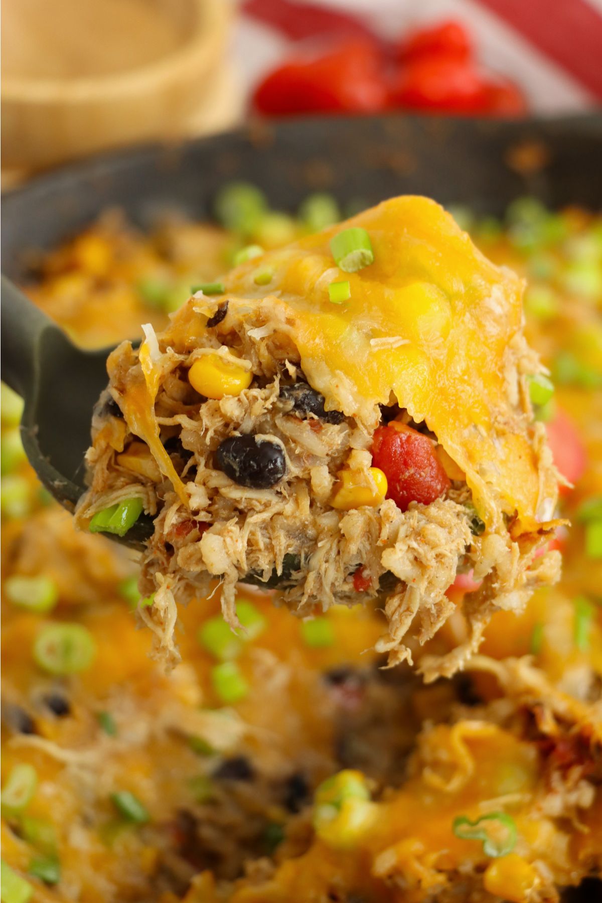 Shredded chicken with green onions, tomatoes and sour cream in a spoon.