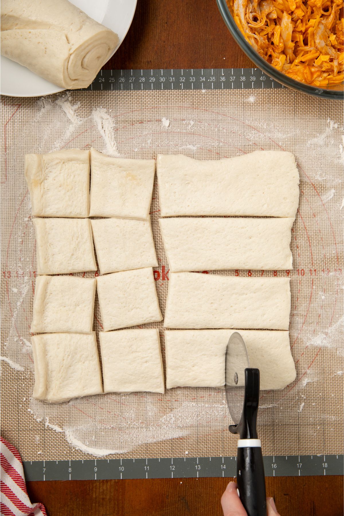 The pizza dough cut into 16 squares. 