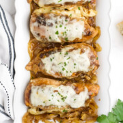 Crockpot French onion chicken placed on a white serving platter after cooking.