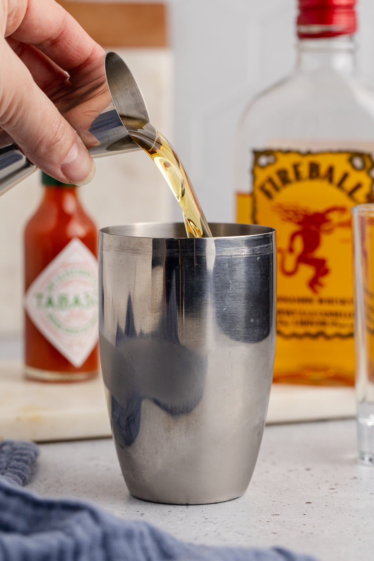 A cocktail shaker with ice, Fireball, white rum and tabasco sauce.
