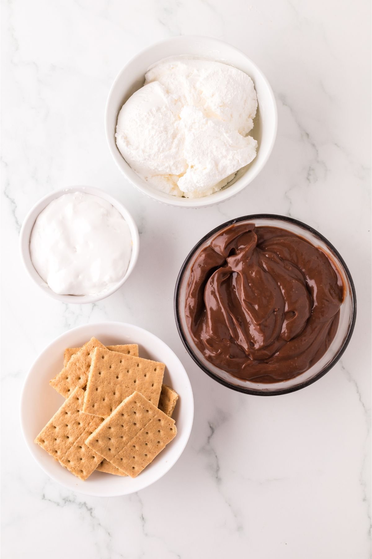 Ingredients for frozen s'mores in bowls on a table.