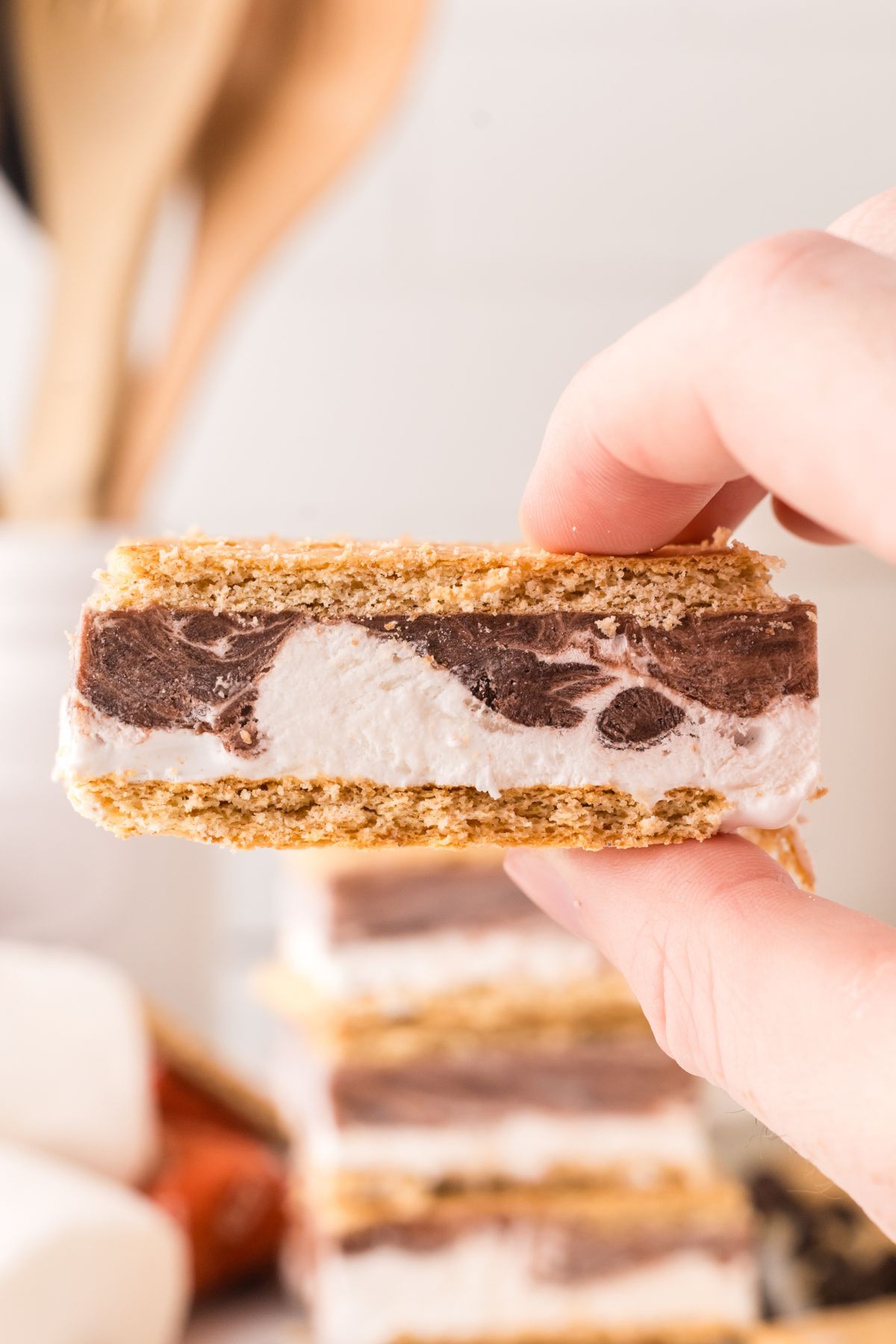 A frozen s'more being held up in the air.