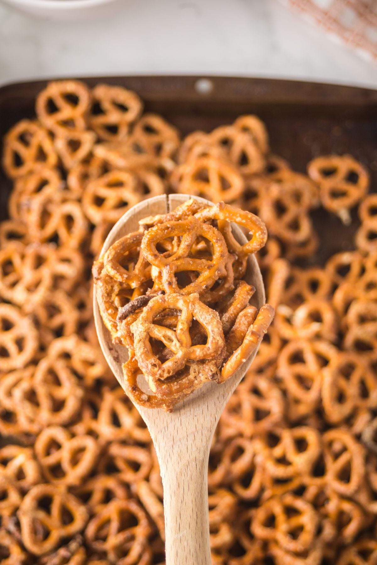Wooden spoonful of pretzels held above the baking sheet.