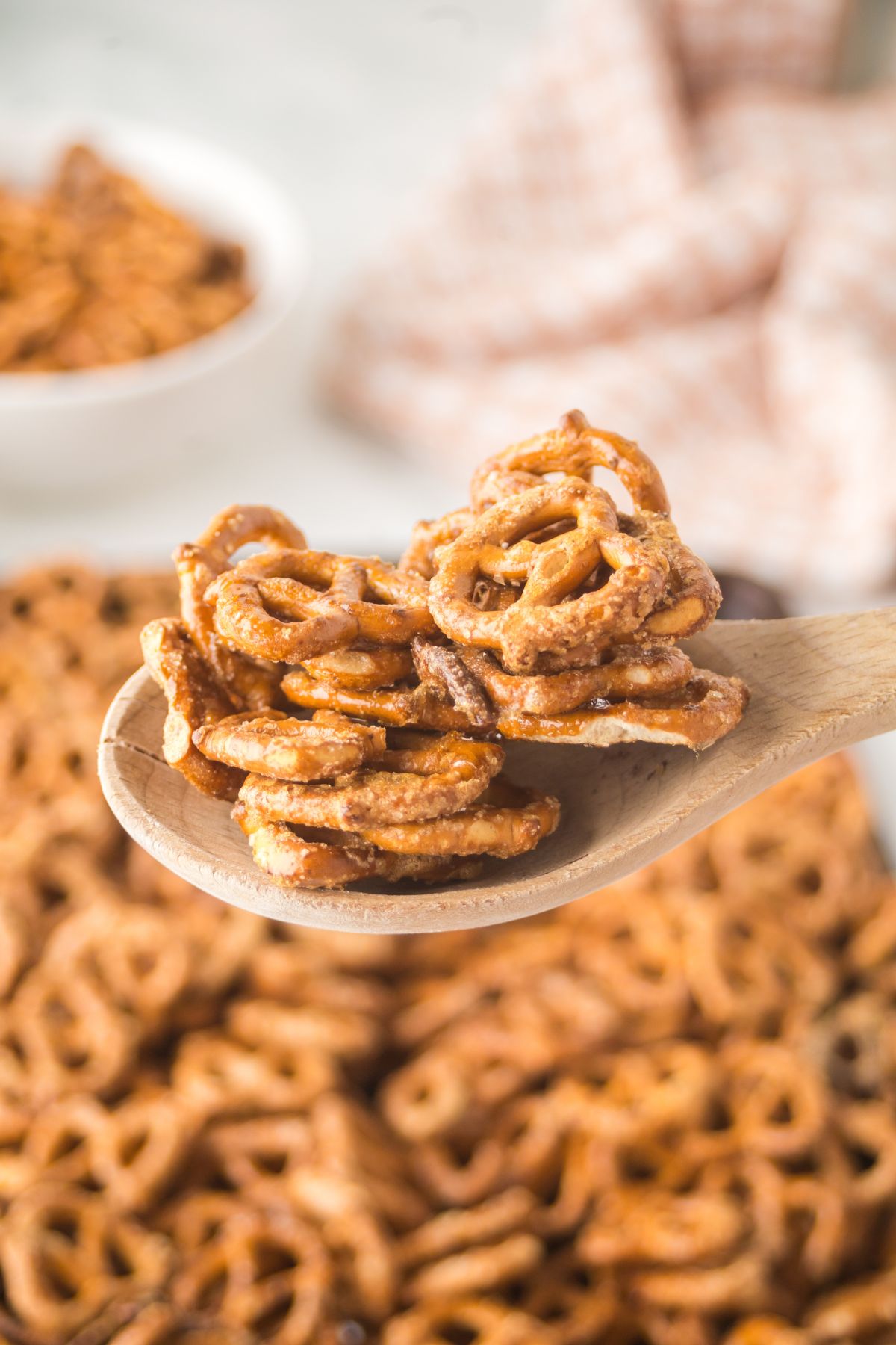 A wooden spoonful of pretzels held above the pan full of them.