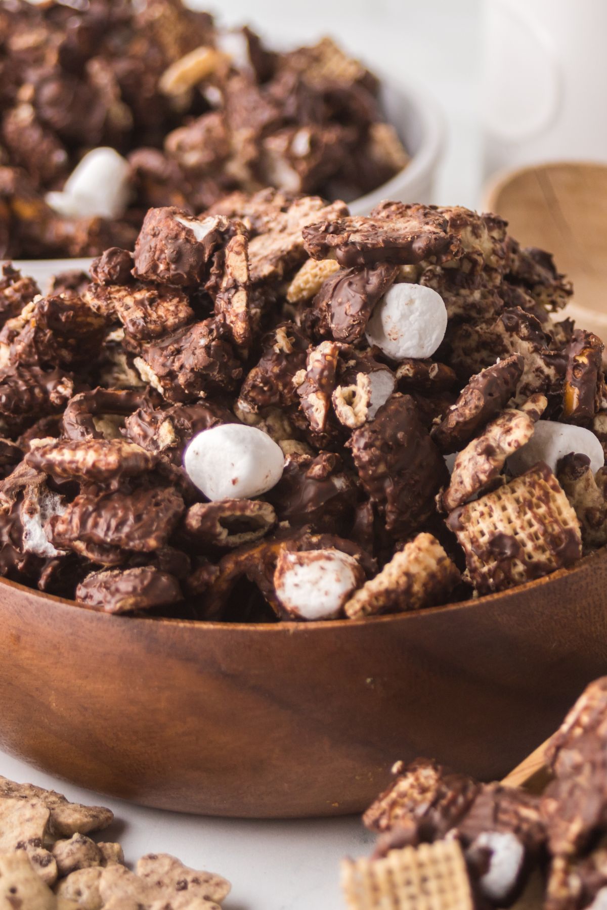 A wooden bowl full of chex mix.