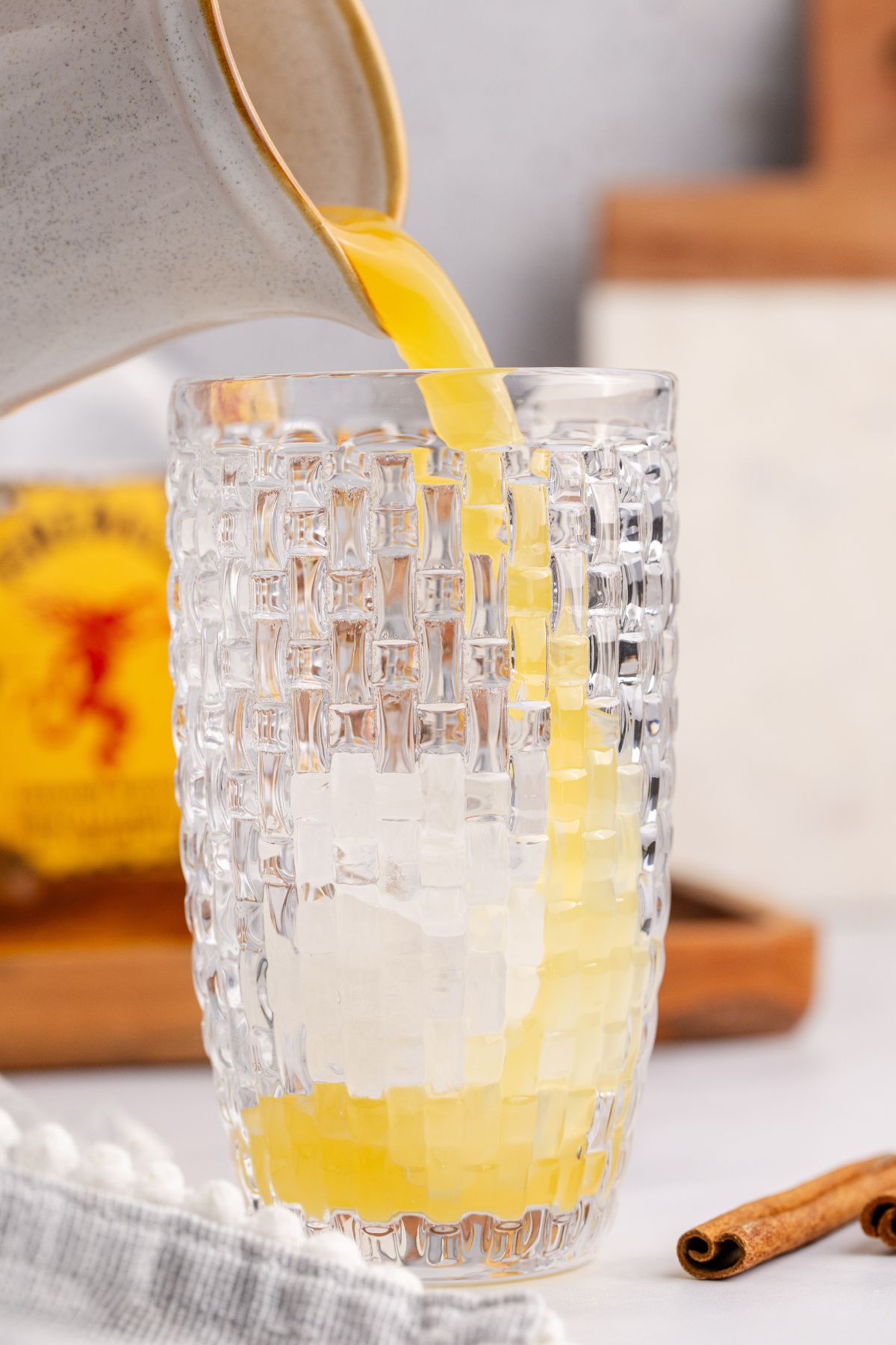Bottom of cocktail shaker filled with ice with ingredients being poured in.