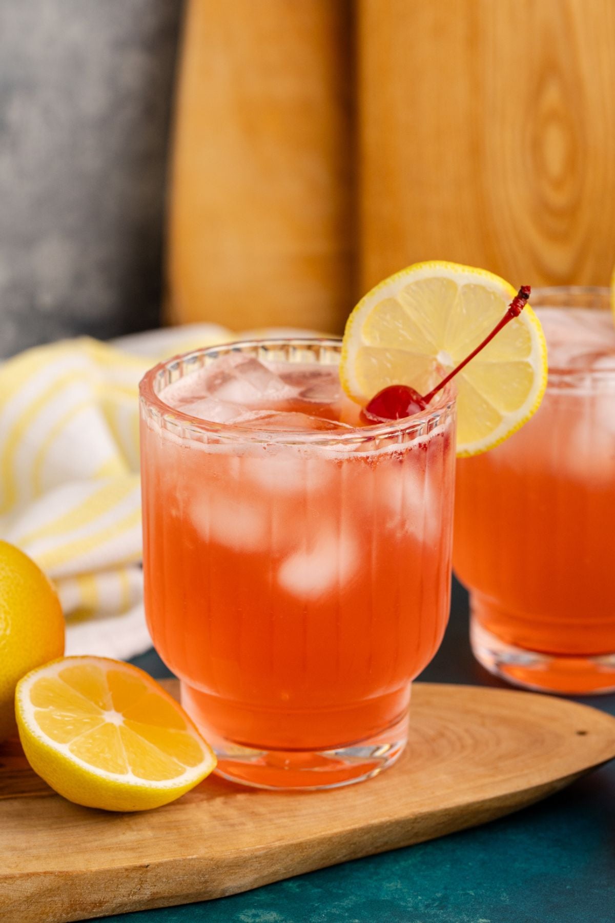 azalea drink garnished with lemon and cherry on a cutting board