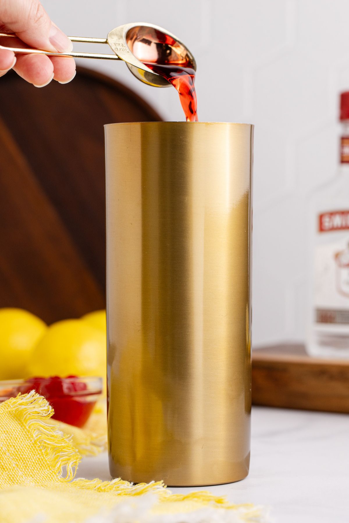 a cocktail shaker filled halfway with ice with lemonade, vodka and grenadine.