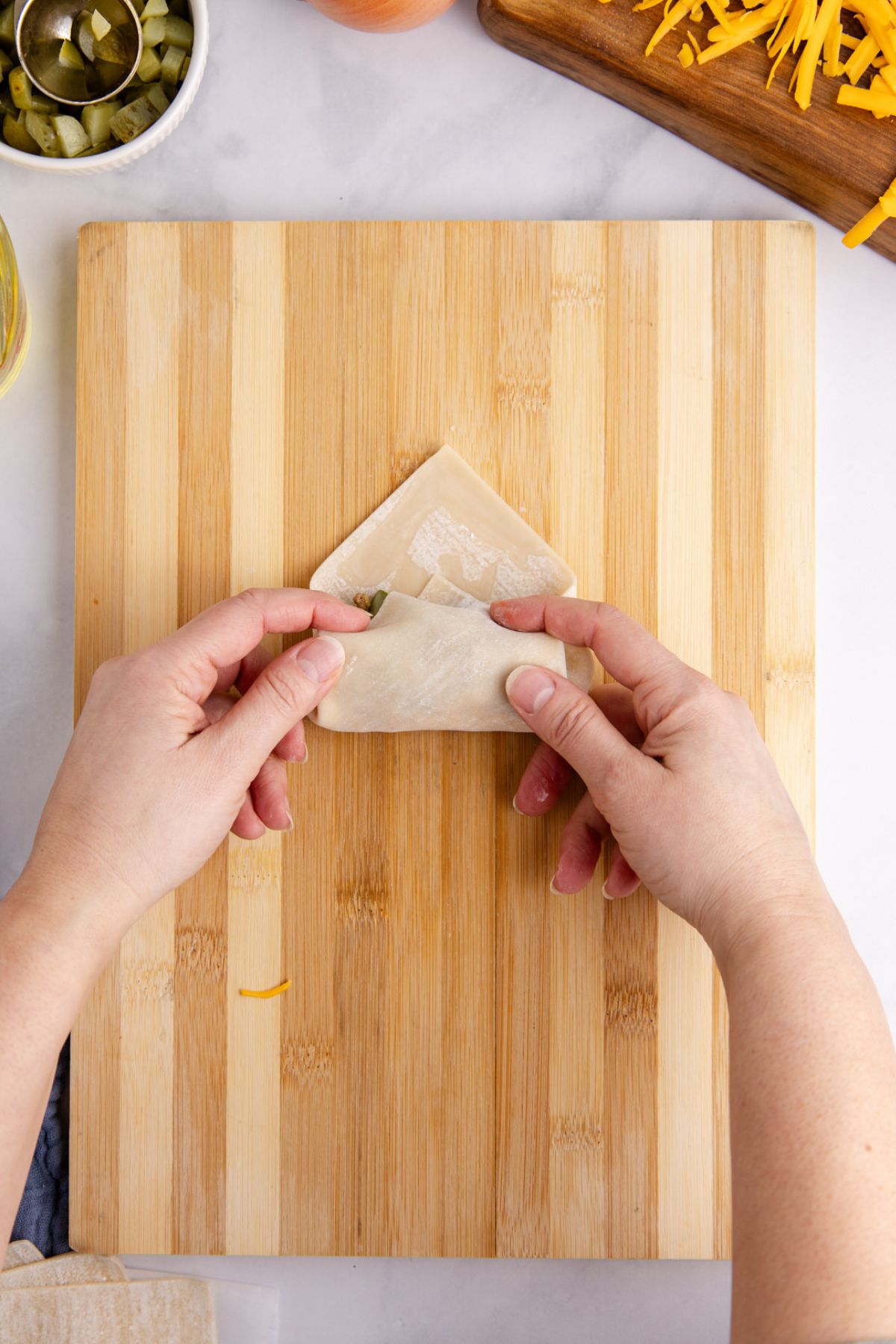 Sealing the egg roll on a cutting board.