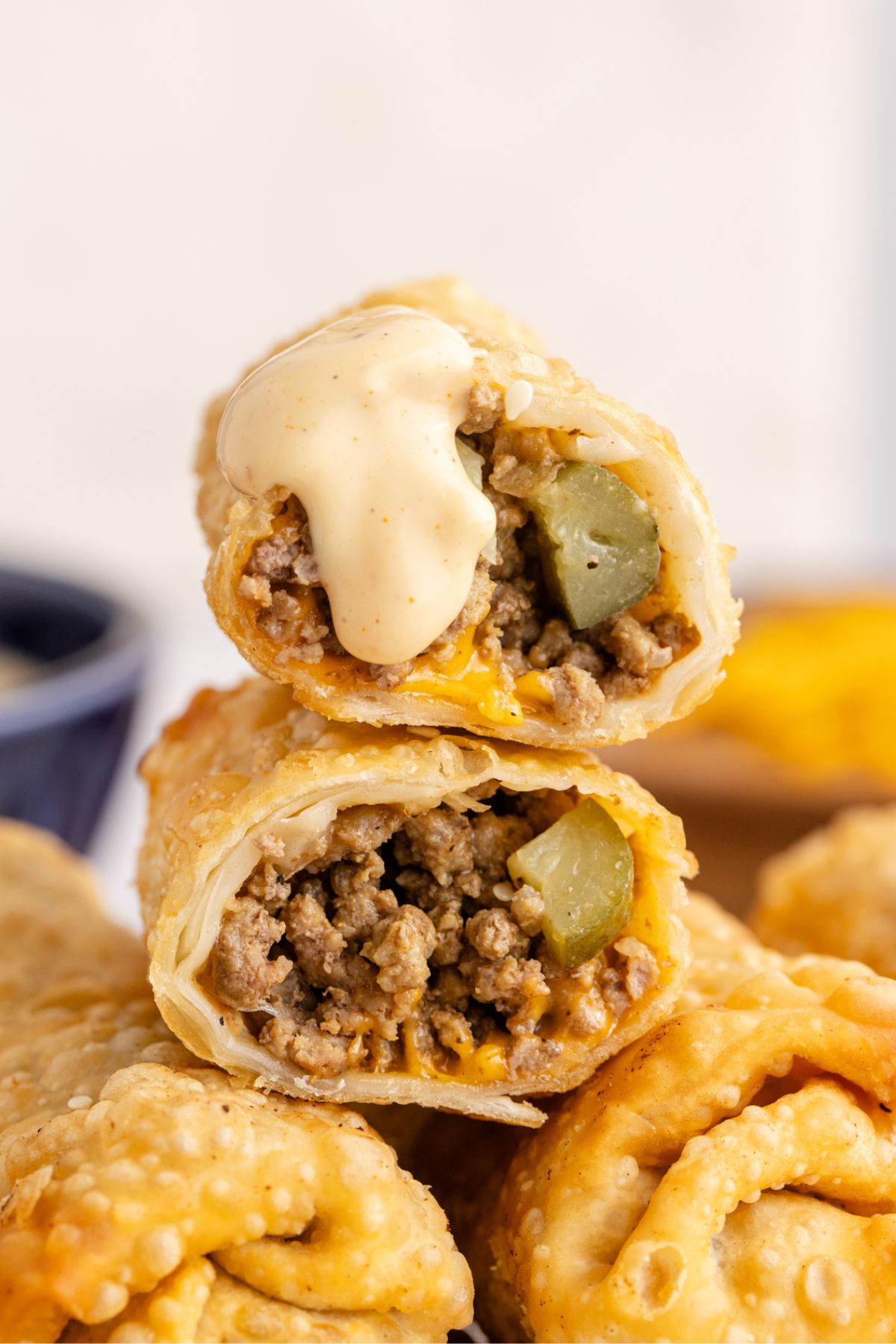 Two halves of an egg roll stacked on top of each other with sauce on the top one.