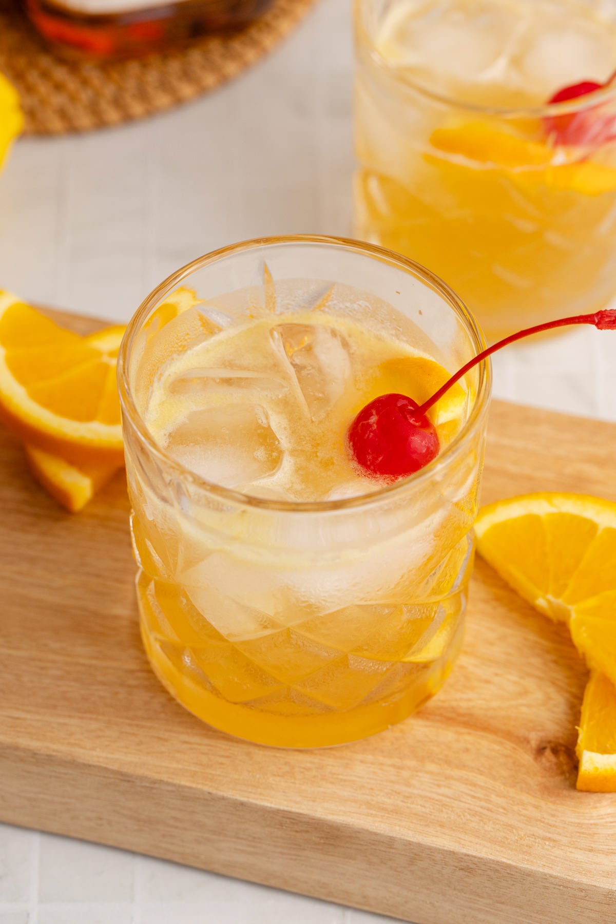 A cocktail served with a cherry garnish on a cutting board.