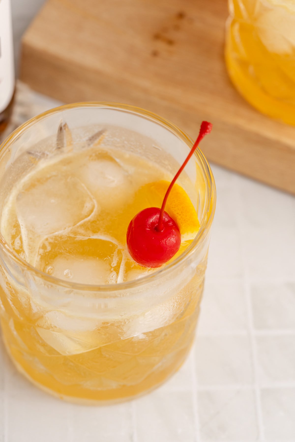 A cocktail served with a cherry garnish on a counter.