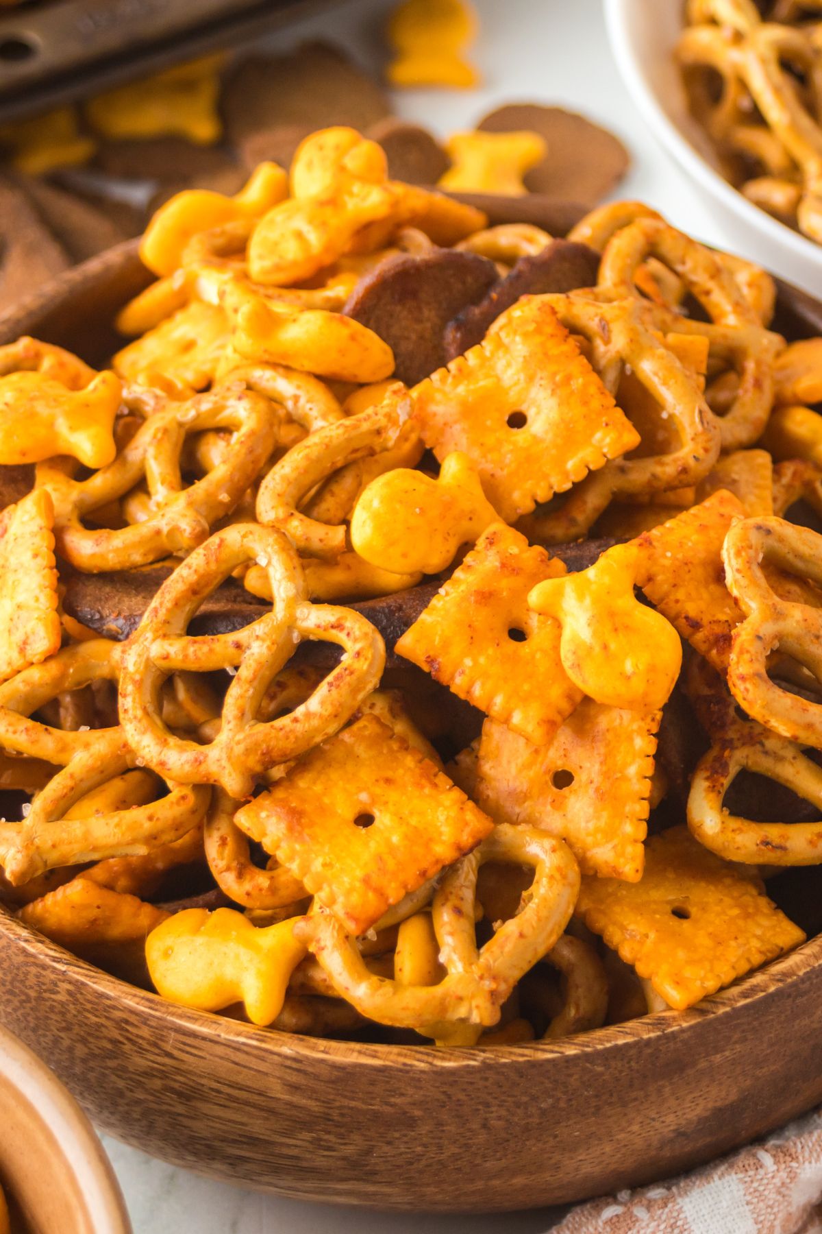 A wooden bowl full of snack mix.
