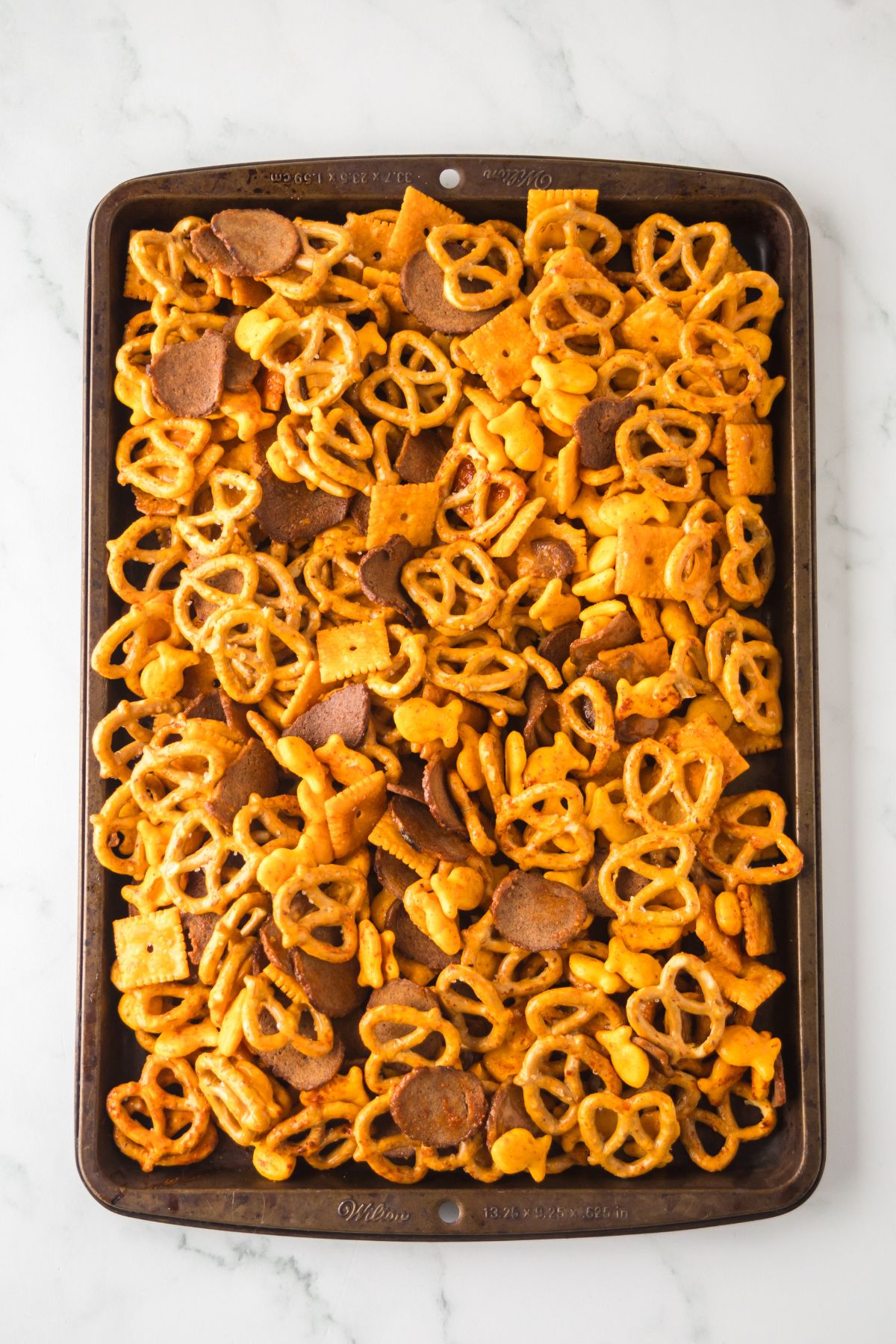 Coated snack mix ingredients in a pan baked and waiting to cool.