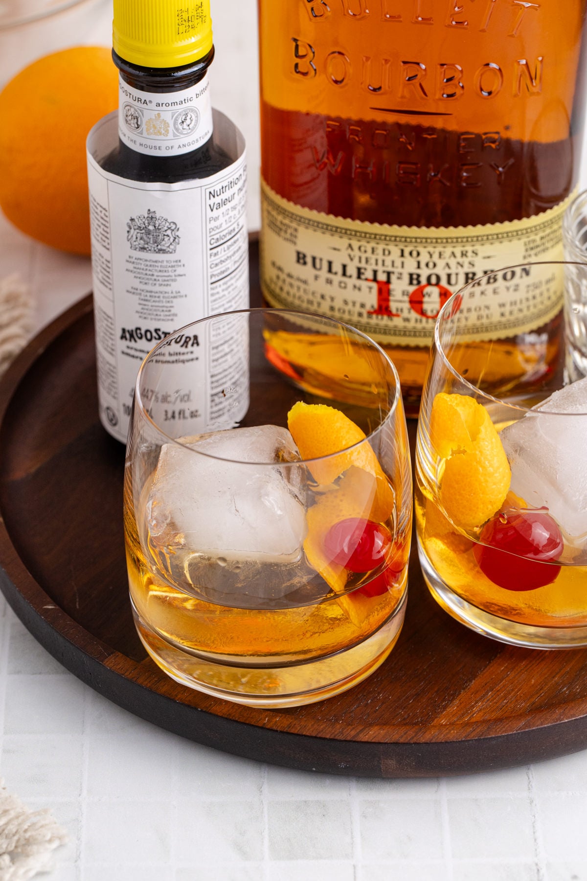Ingredients to make drink and two drinks on a wooden tray