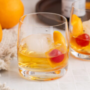 A bulleit old fashioned on the rocks with a cherry and orange peel garnish.