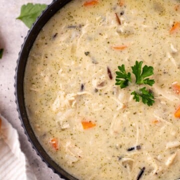 A bowl of chicken and wild rice soup being served in a bowl.