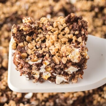 Popcorn bars in a pan with a spatula holding one up and over the dish.
