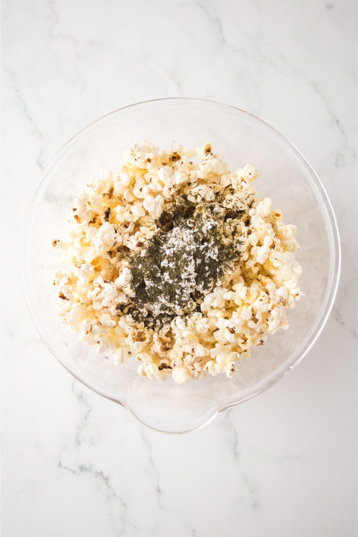 A bowl of popcorn covered in butter and seasoning. 