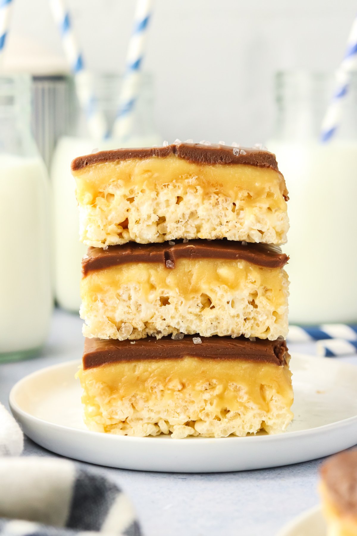 A stack of three chocolate covered rice krispie treats on a plate.