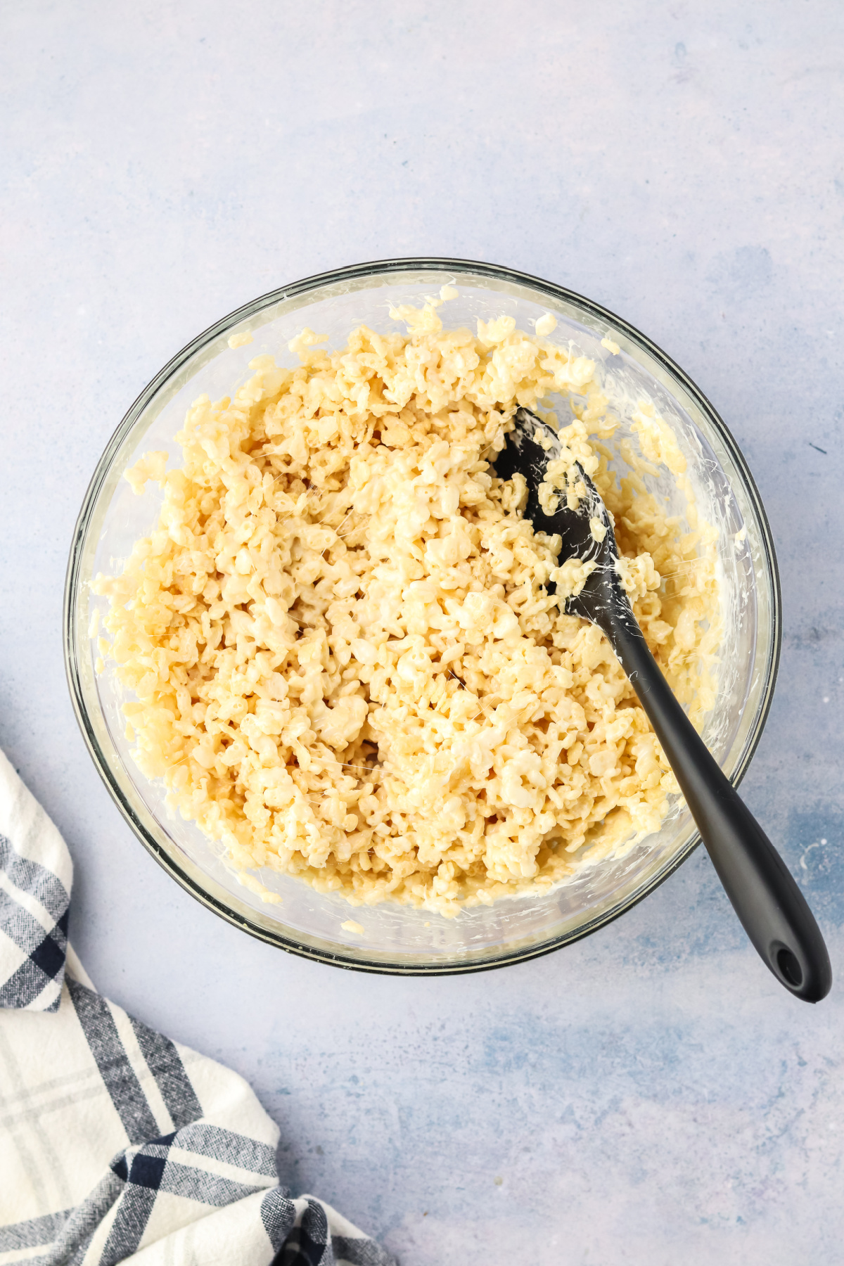 Vanilla extract and rice krispies coated in marshmallows in a bowl.