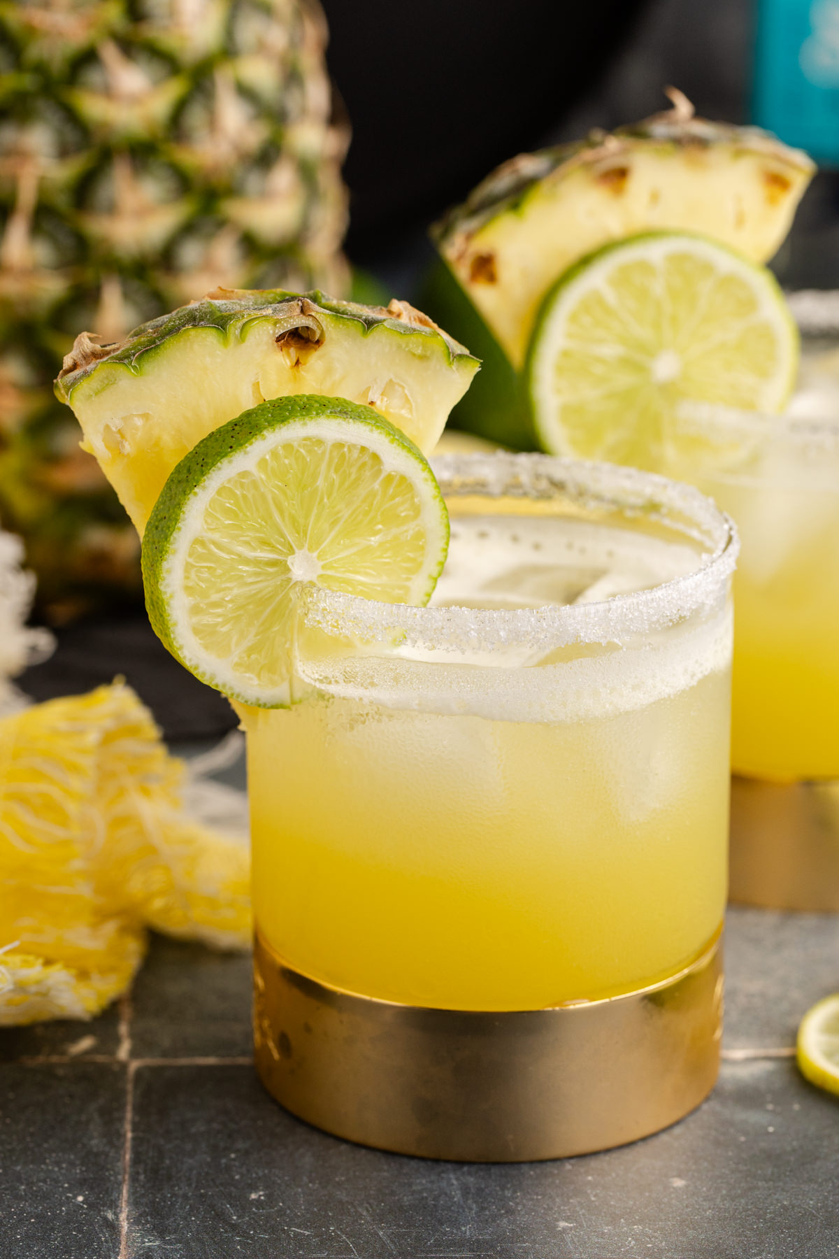 Margarita with pineapple juice in a glass with lime and pineapple garnish.
