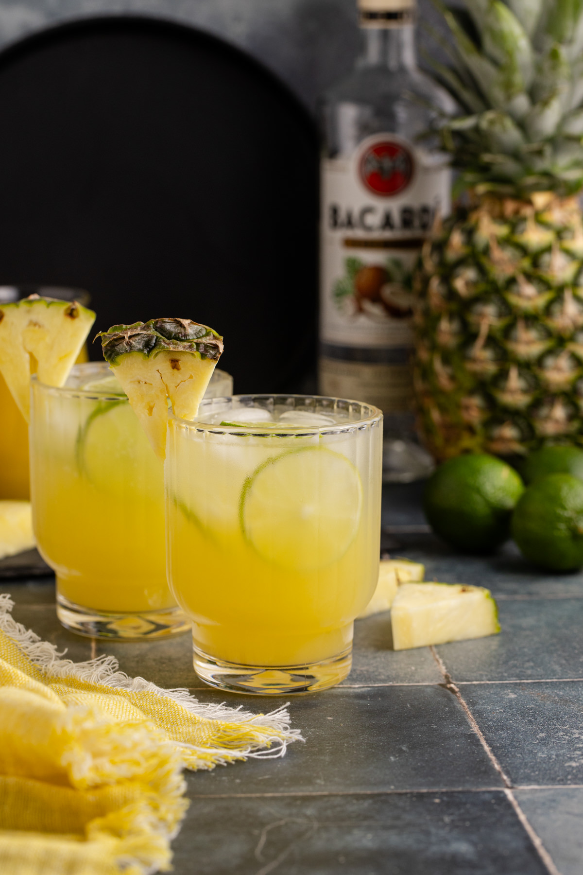 Two glasses of rum cocktail with a wedge of pineapple on the rim.