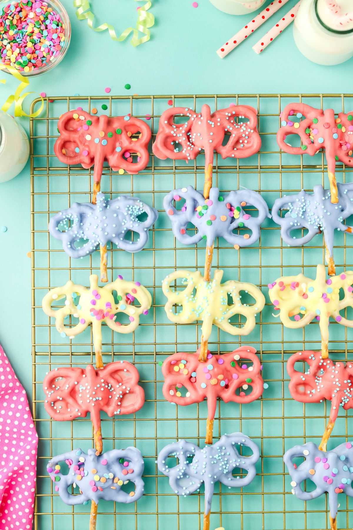 Different colored butterfly pretzels on a cooling rack.