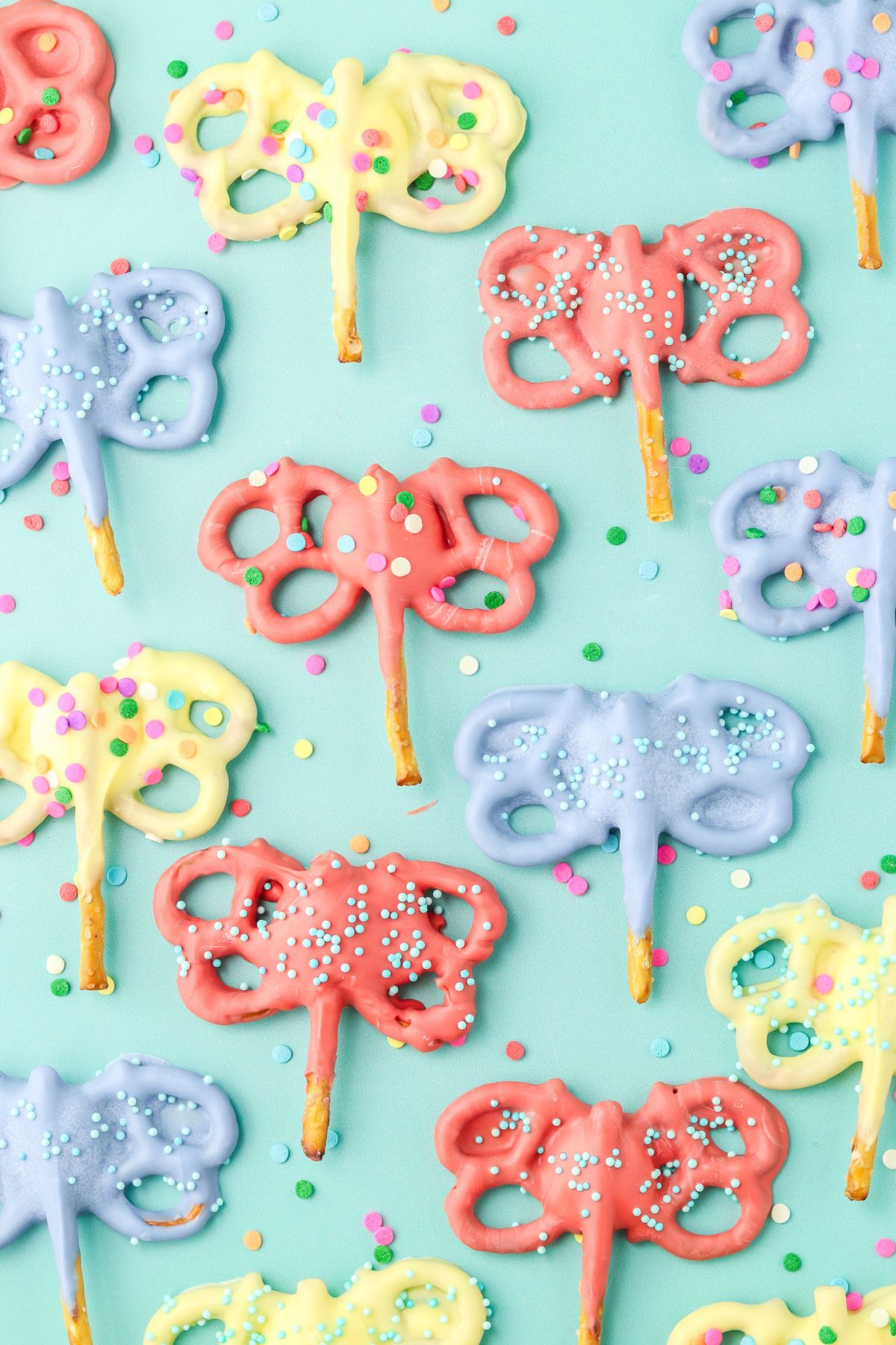 A bunch of pretzels in the shape of a butterfly dipped in candy melt with sprinkles.