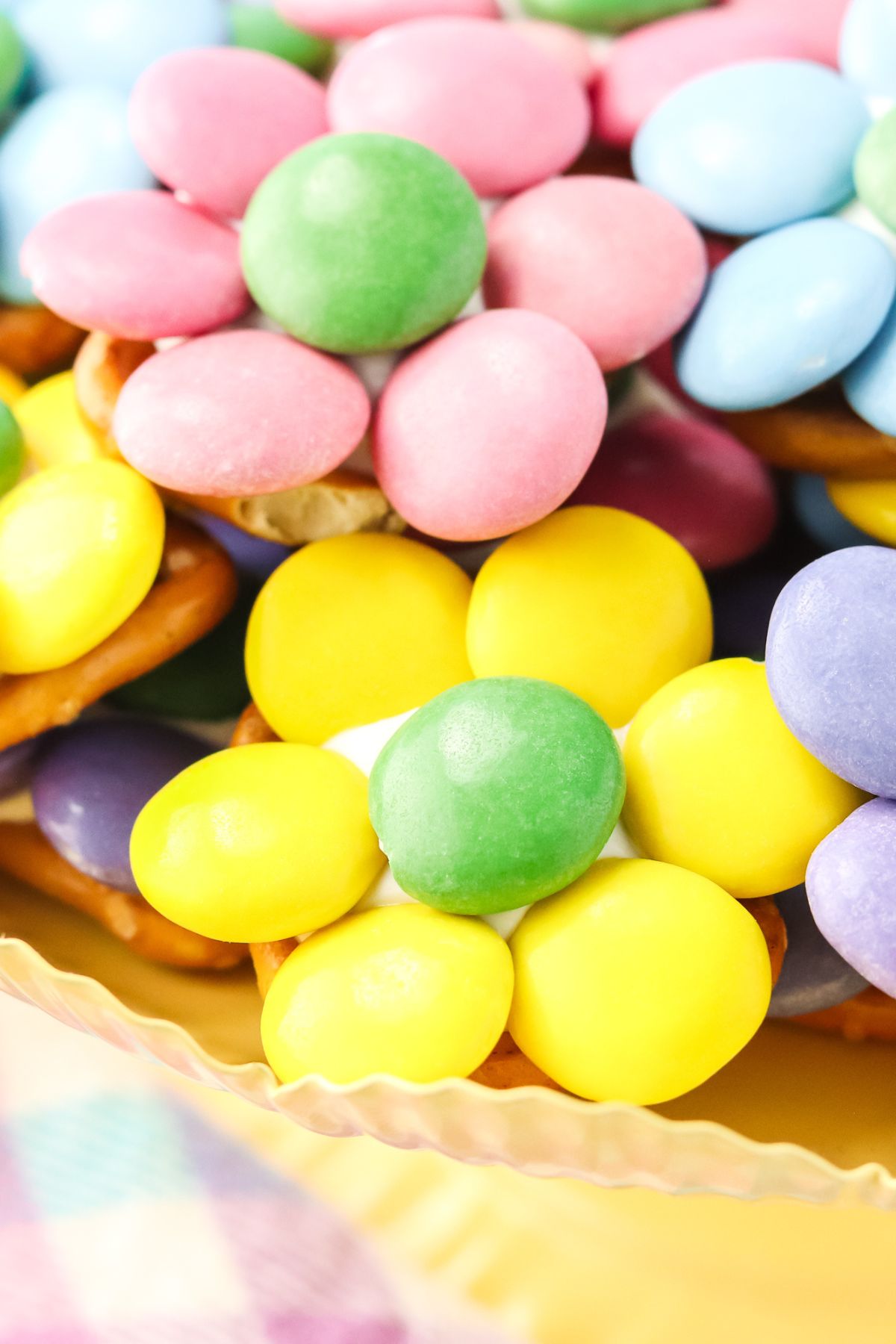 M&M's shaped like a flower over a pretzel and candy melt.