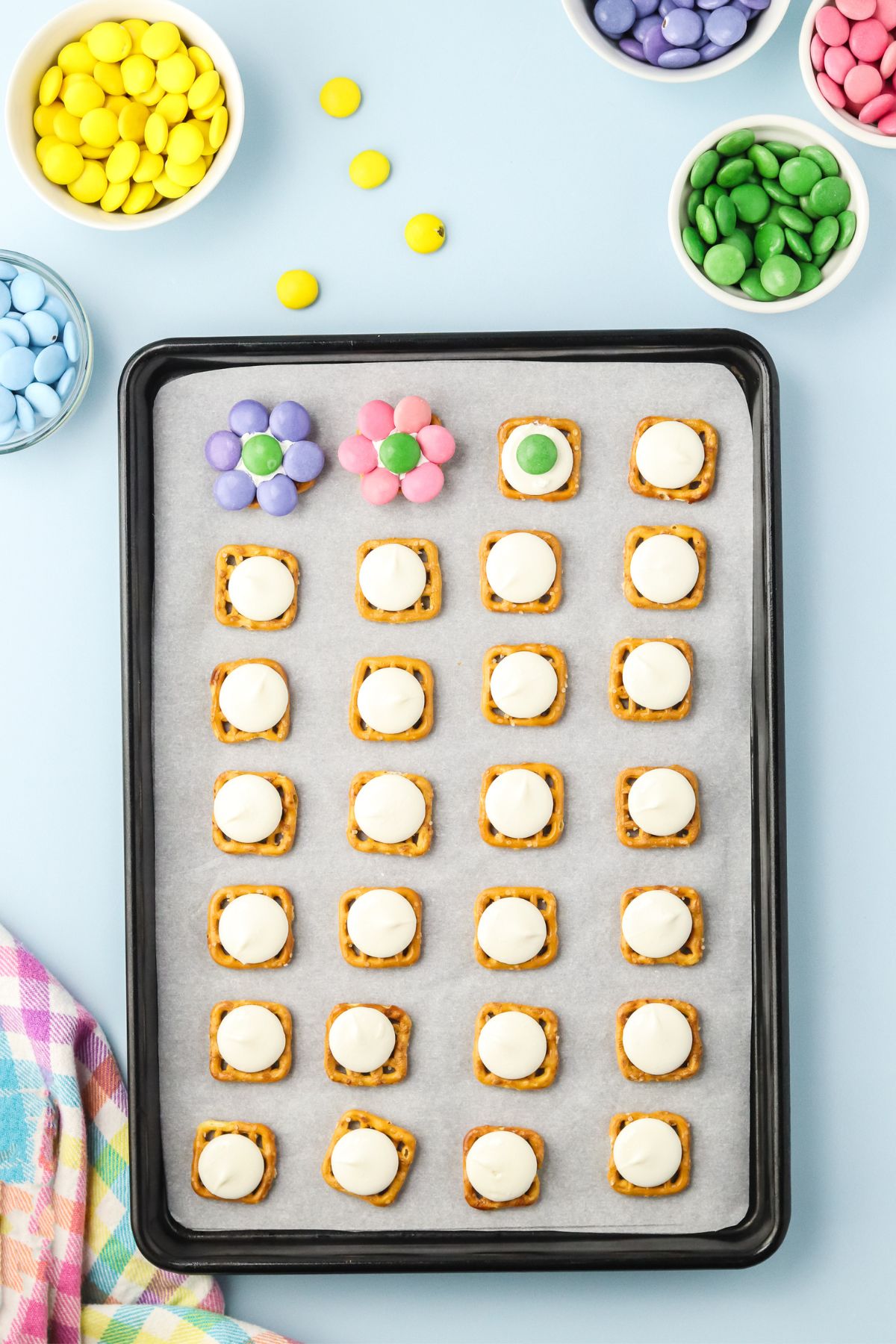 Waffle pretzels with a candy melt on top and M&M in the center and around creating a flower pattern.