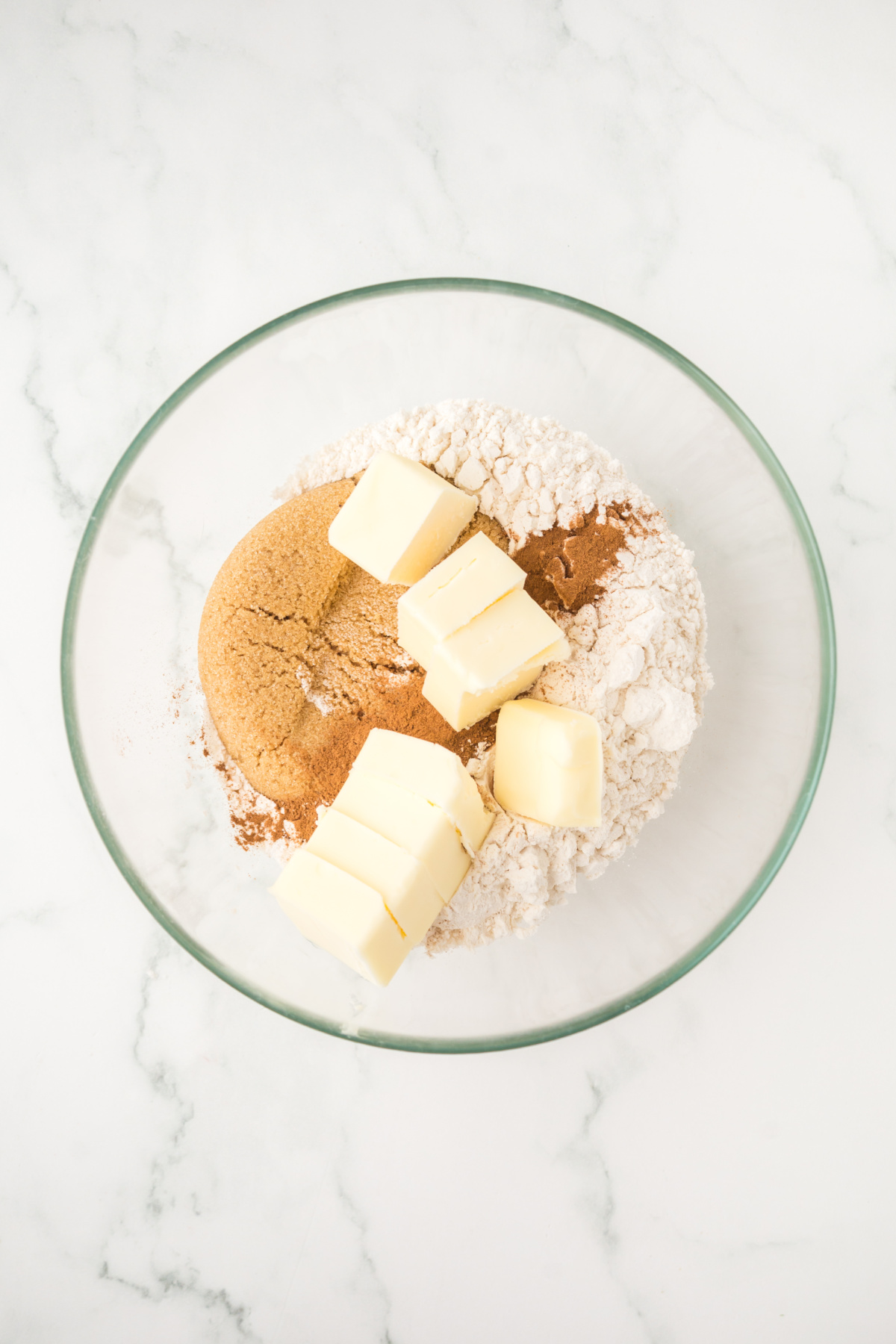 Cold butter with flour, cinnamon, and brown sugar in a mixing bowl.