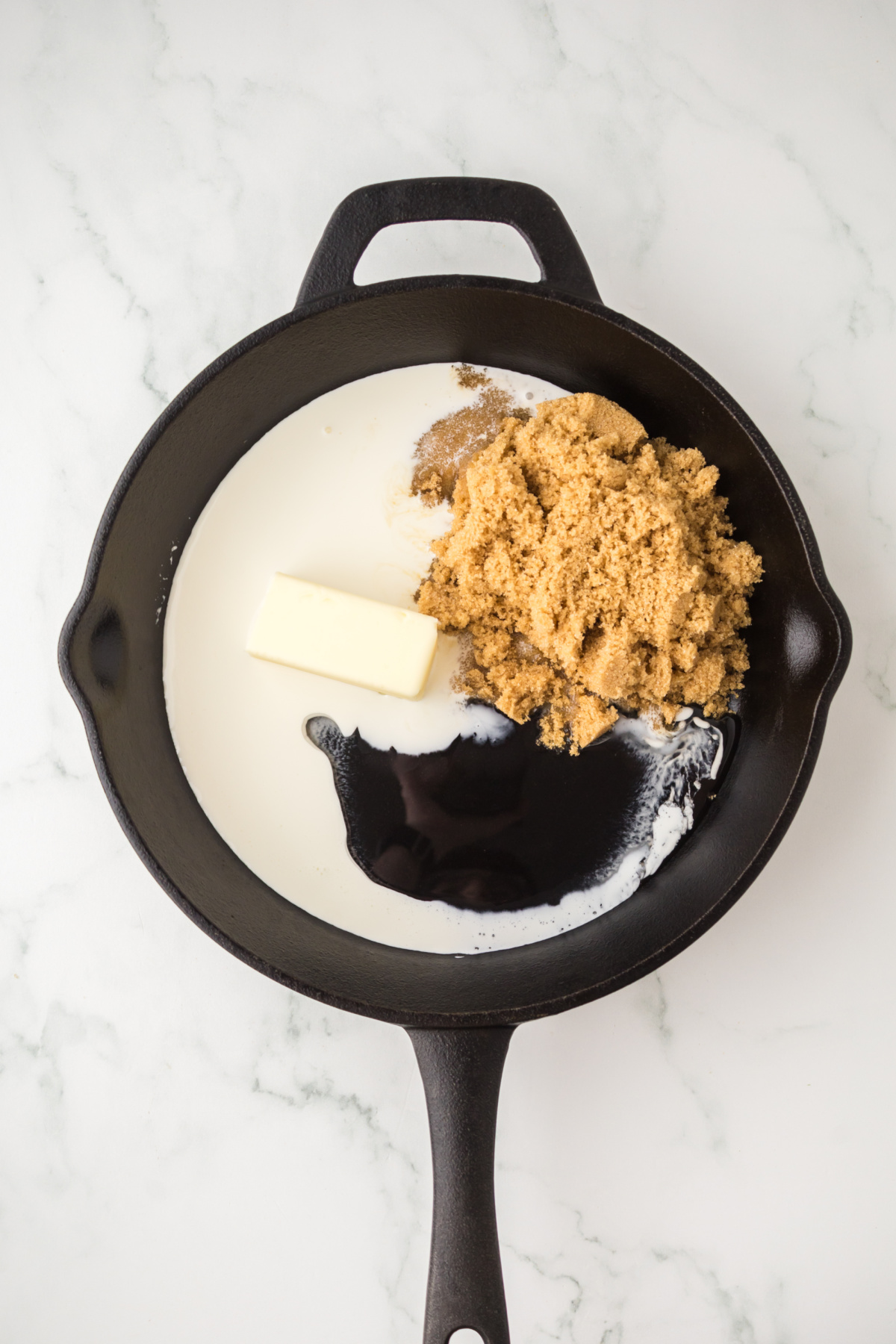 Butter, corn syrup, heavy cream, and brown sugar heating in a skillet.