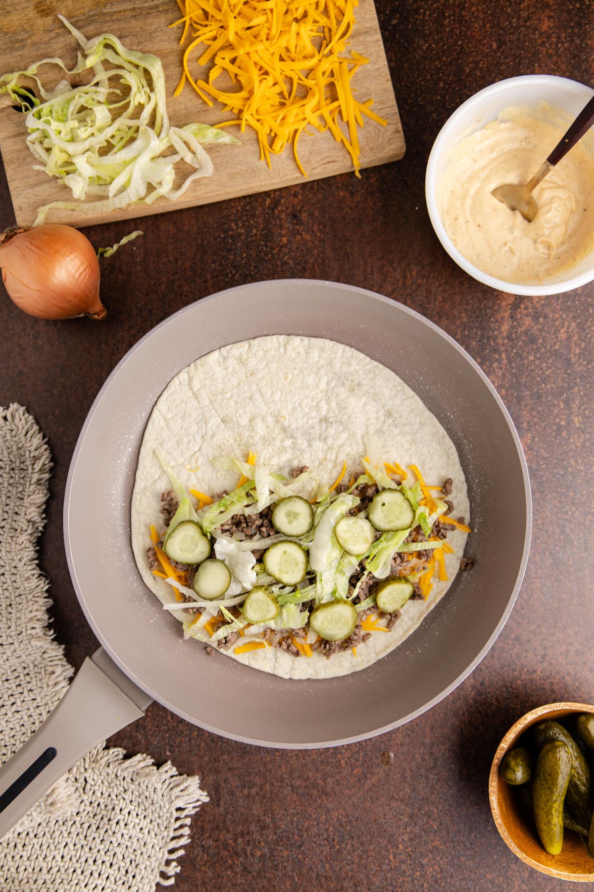 Cheese, beef, lettuce, and pickles on a wrap.