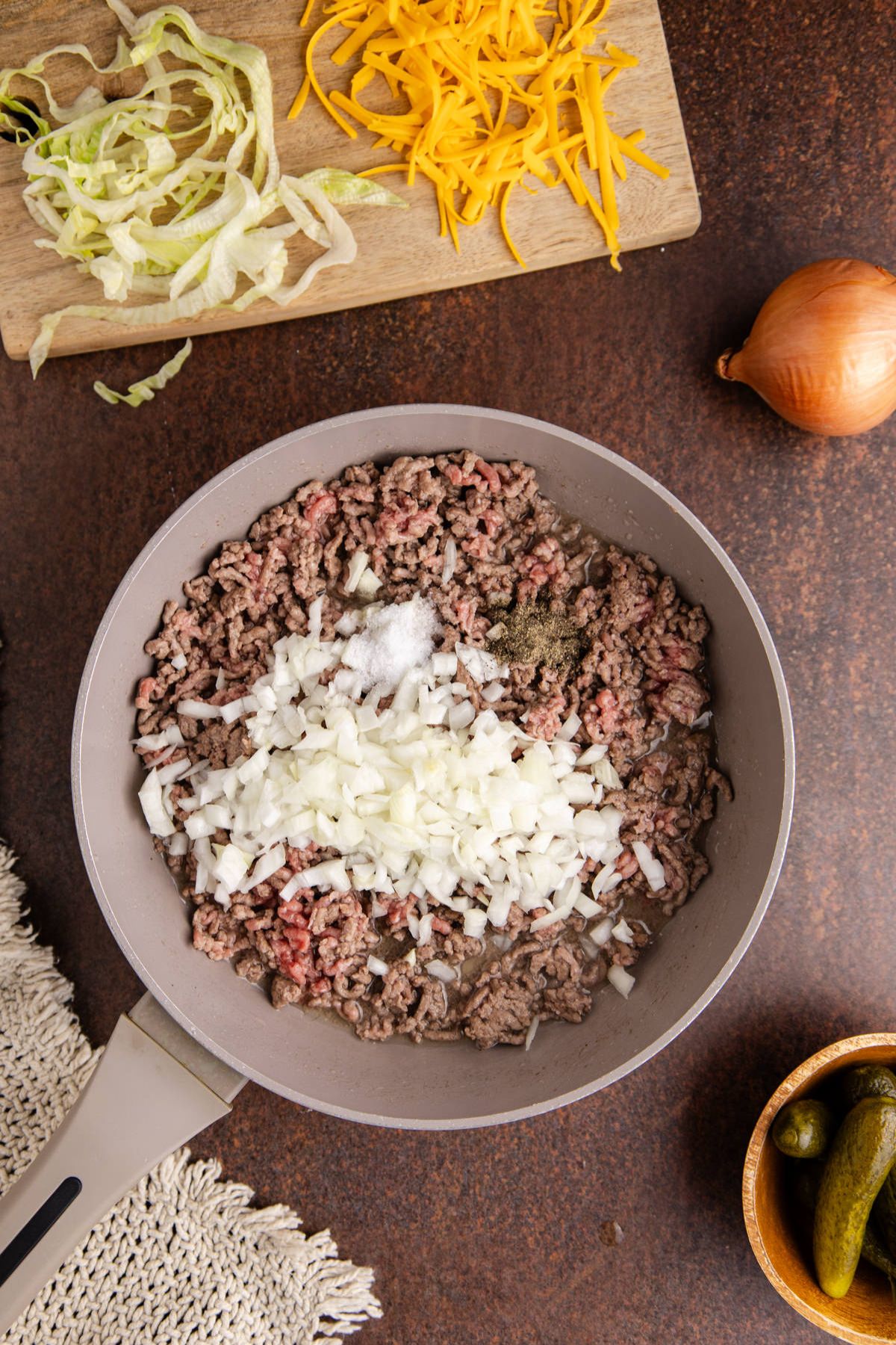 Onions and ground beef in a skillet cooking.