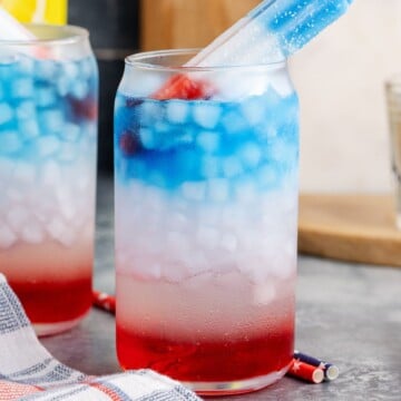 A glass of Bomb Pop Cocktail topped with a popsicle.