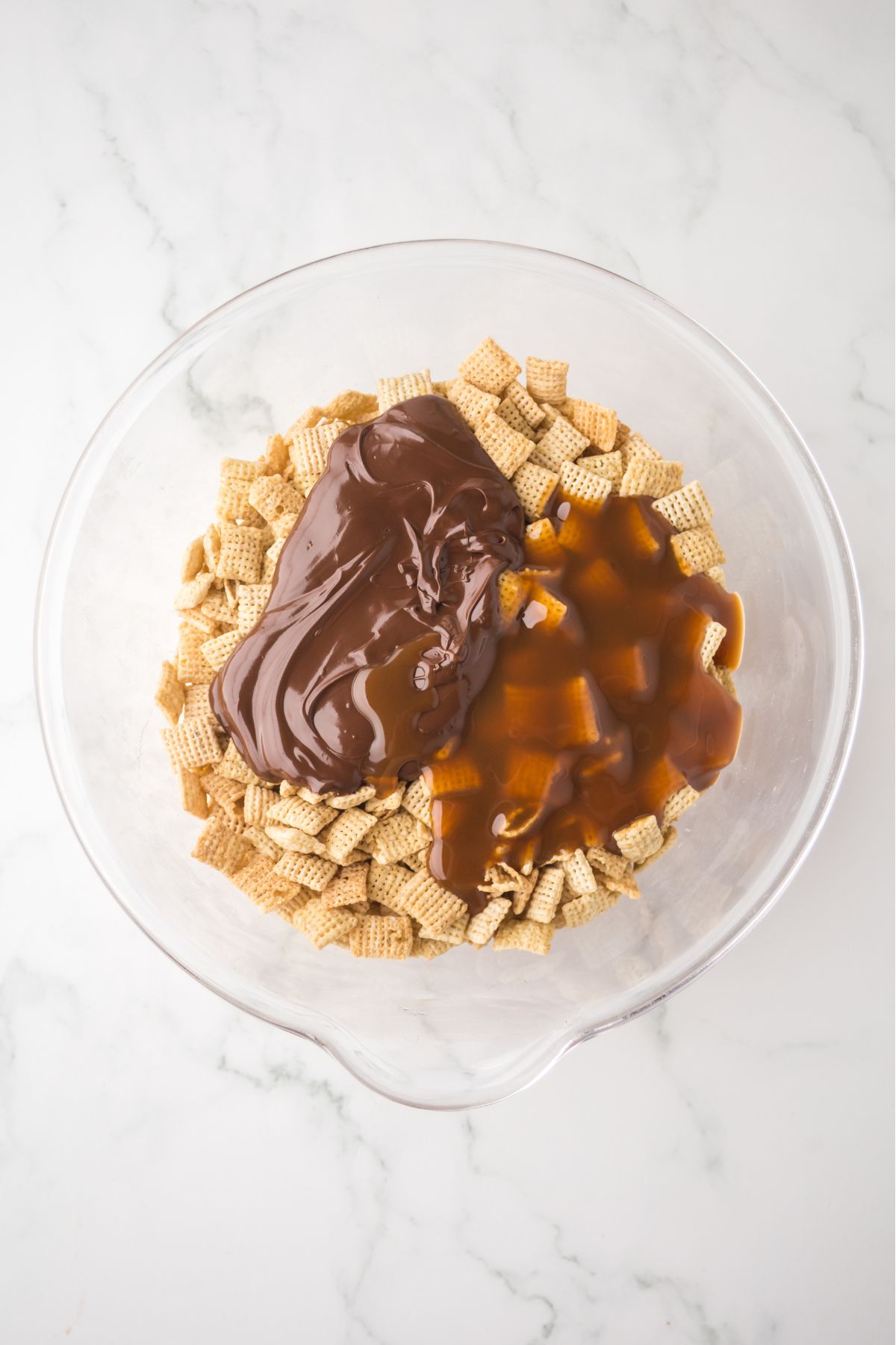 Caramel and chocolate sauce added to chex cereal in a bowl.