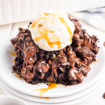 Chocolate pudding cake on a stack of plates with ice cream on top.
