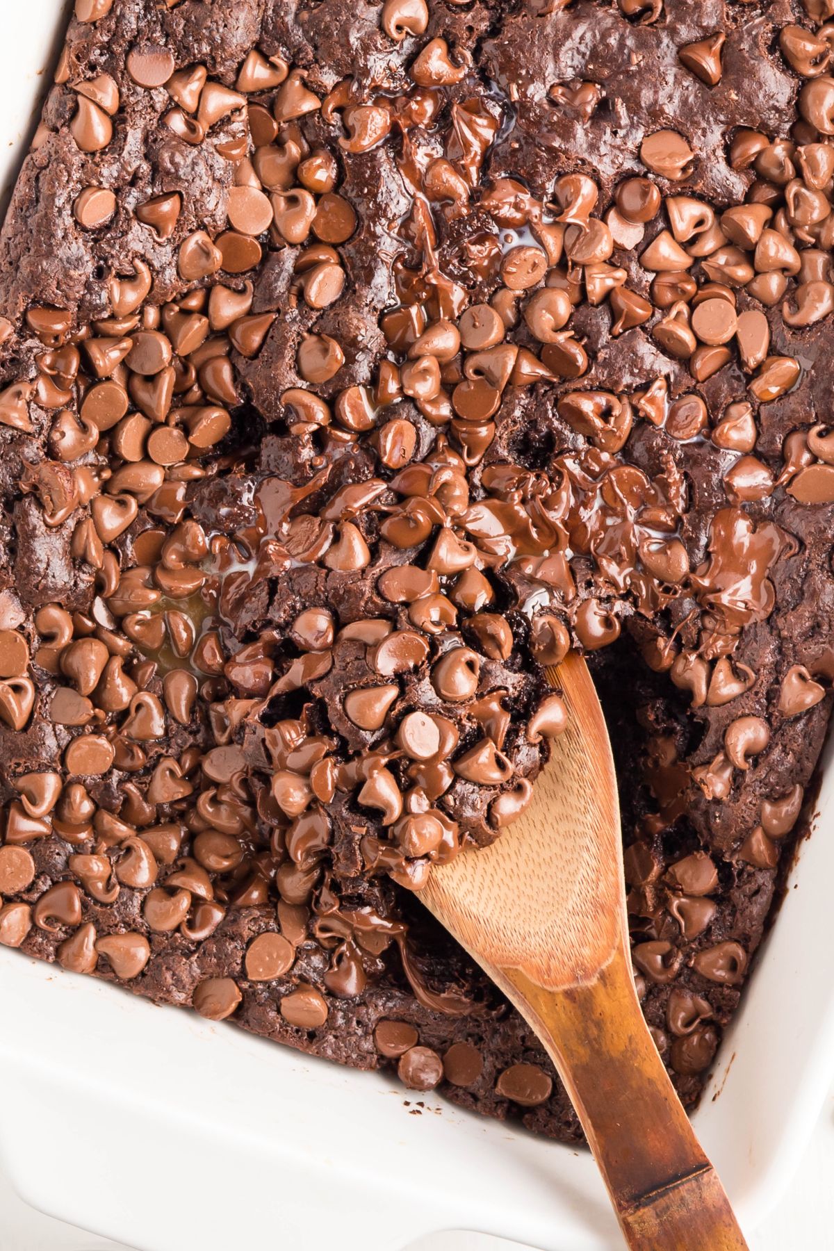 A scoop of pudding cake being taken out with a wooden spoon.