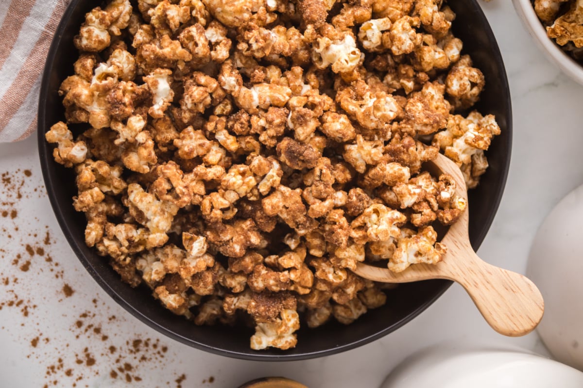 A bowl of popcorn with a scoop in it.