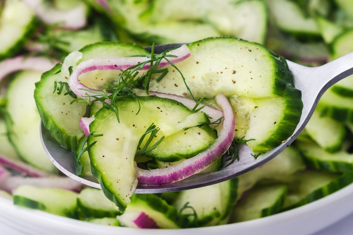 Cucumber Onion Salad being held up by a spoon.