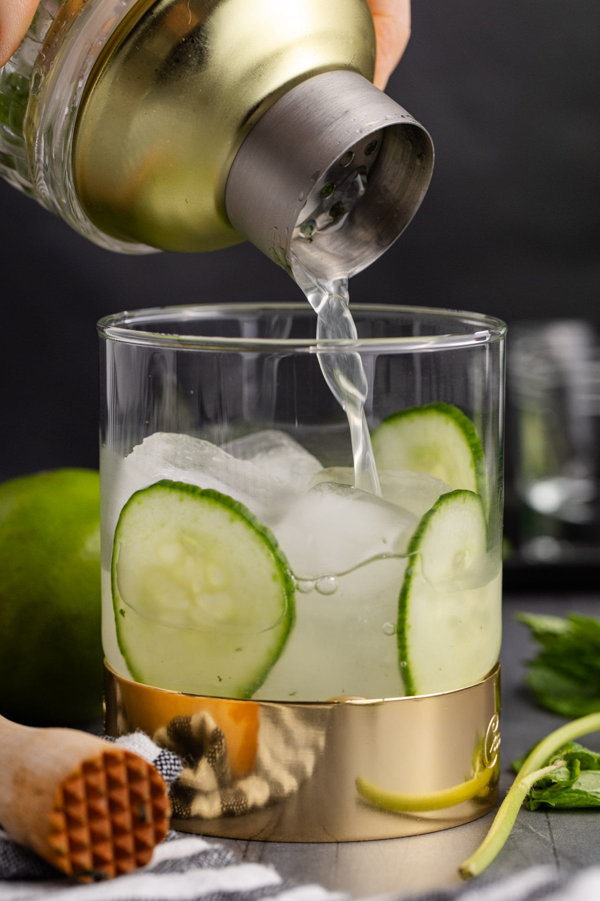 Shaken cocktail shaker being strained as it pours into a glass with ice