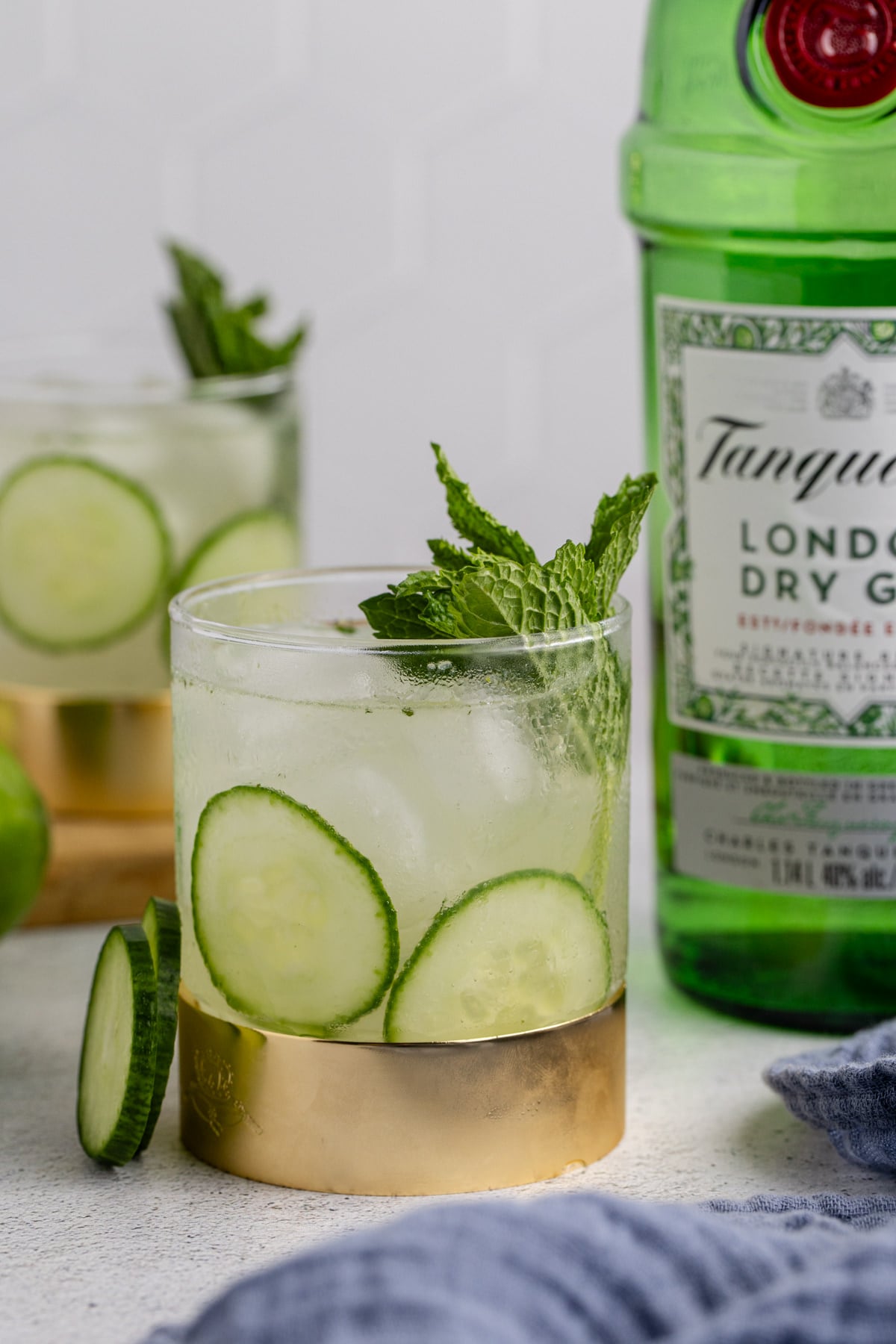 A garnished cocktail on a table with a bottle of gin.