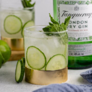A garnished East Side Cocktail on a table with a bottle of gin.