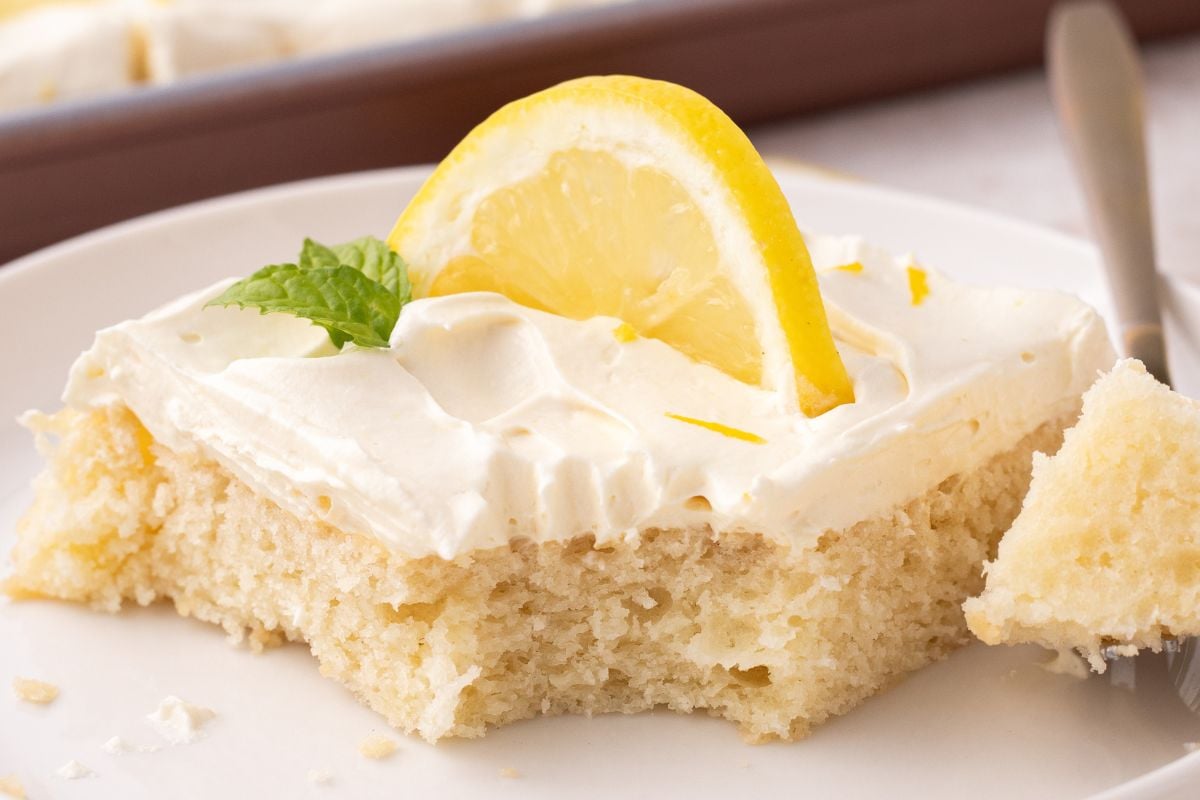 A slice of cake on a plate missing a fork bite.